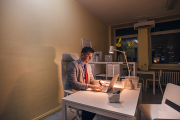 Serious doctor working on his laptop ( pc ) at night, overtime.