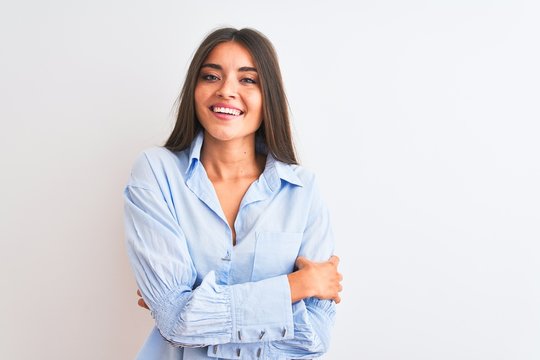 Young beautiful woman wearing blue elegant shirt standing over isolated white background happy face smiling with crossed arms looking at the camera. Positive person.