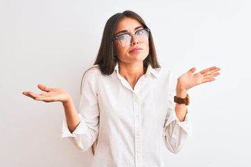 Young beautiful businesswoman wearing glasses standing over isolated white background clueless and...