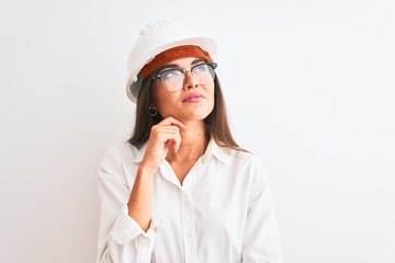 Young beautiful architect woman wearing helmet and glasses over isolated white background with hand on chin thinking about question, pensive expression. Smiling with thoughtful face. Doubt concept.