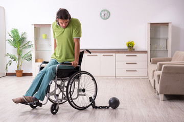Young male invalid in wheel-chair suffering at home