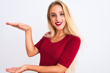 Young beautiful woman wearing red t-shirt standing over isolated white background gesturing with hands showing big and large size sign, measure symbol. Smiling looking at the camera
