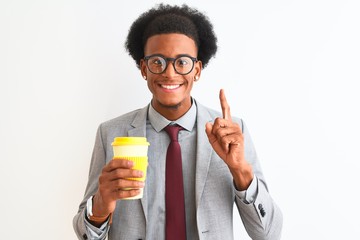 Fototapeta premium African american businessman drinking cup of coffee over isolated white background surprised with an idea or question pointing finger with happy face, number one