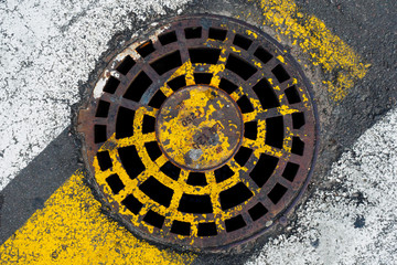 Rusty sewer hatch at a pedestrian crossing. The concept of old communications, the need for repair.