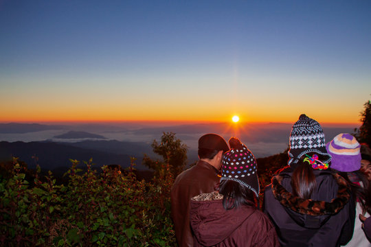 Tourists watch the sunrise at misty morning mountains the Doi Pha Hom Pok viewpoint, Thailand.