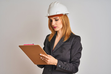 Young beautiful redhead architect woman wearing suit and hardhelmet holding flip board