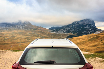 Fototapeta na wymiar Autumn mountain landscape. View from behind a white car. Durmitor National Park, Montenegro. Focus on the mountains
