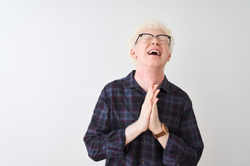 Young albino blond man wearing casual shirt and glasses over isolated white background begging and...