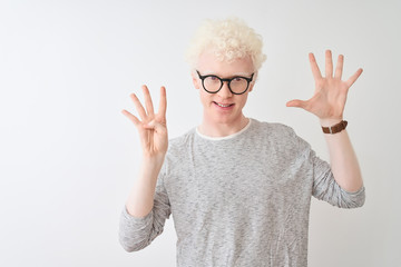 Young albino blond man wearing striped t-shirt and glasses over isolated white background showing and pointing up with fingers number nine while smiling confident and happy. - obrazy, fototapety, plakaty