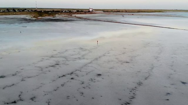 A girl in a black swimsuit stands in the water and looks at the sunset. A young woman sunbathing by a salt lake. A zoom-in effect. salt lake Burlin, bursol. Altai. Siberia Russia