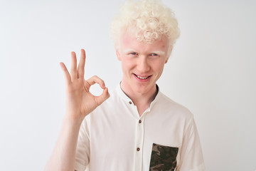 Young albino blond man wearing casual shirt standing over isolated white background doing ok sign with fingers, excellent symbol