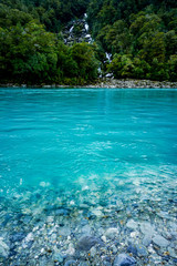 Fototapeta na wymiar New Zealand tourism glacial blue river with waterfall