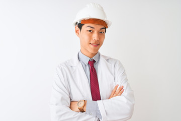 Chinese architect man wearing coat and helmet standing over isolated white background happy face smiling with crossed arms looking at the camera. Positive person.