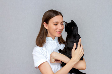 Girl doctor in a white coat. Vet in uniform with a black cat. Medicine concept