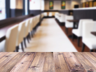 Wood table top over abstract blur background of cafe or restaurant interior.