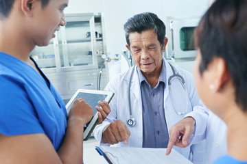 Group of medical workers checking document with medical history of patient before performing surgery