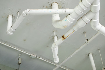 Water leakage from the sewer in building. Pipeline leaked with dirty water droping to the floor. Sewer pipes system in ceiling of building.