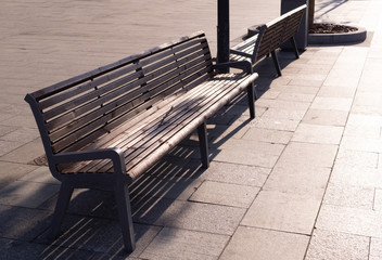 Fototapeta na wymiar brown wooden bench on the street at sunset. furniture, city.