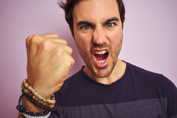 Young handsome man wearing casual t-shirt standing over isolated pink background annoyed and frustrated shouting with anger, crazy and yelling with raised hand, anger concept