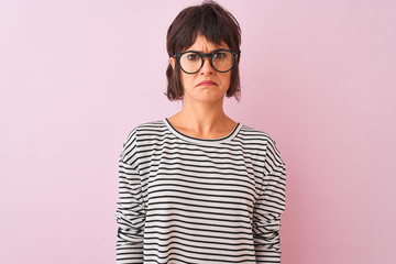 Young beautiful woman wearing striped t-shirt and glasses over isolated pink background depressed and worry for distress, crying angry and afraid. Sad expression.