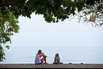 Happy mother, child relaxing and talking on luxury hotel veranda with beautiful view. People...