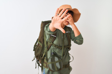 Hiker woman wearing backpack hat and water canteen over isolated white background covering eyes with hands and doing stop gesture with sad and fear expression. Embarrassed and negative concept.
