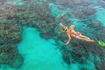 Happy family - mother, kid in snorkeling mask dive underwater, explore tropical fishes in coral...