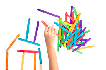 Hand of children is connecting the colorful popsicle sticks joyfully isolated on white background.