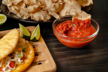 plate with taco, nachos chips and tomato dip. Spicy Nachos (close-up shot) on rustic wooden background