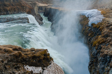 A three-step staircase of the Gullfoss waterfall on Hvita river, as pictured in detail (water plunging into the canyon, mossy cliffs, thick spray, panorama of the rapids)