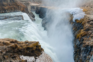 A three-step staircase of the Gullfoss waterfall on Hvita river, as pictured in detail (water plunging into the canyon, mossy cliffs, thick spray, panorama of the rapids)