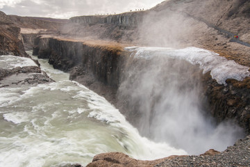 A three-step staircase of the Gullfoss waterfall on Hvita river, as pictured in detail (water plunging into the canyon, mossy cliffs, thick spray, panorama of the rapids)