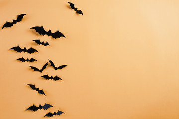 Top view of Halloween crafts, black paper bats flying over orange background with copy space for text. halloween concept.