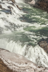 A three-step staircase of the Gullfoss waterfall on Hvita river, as pictured in detail (water plunging into the canyon, mossy cliffs, thick spray, panorama of the rapids)