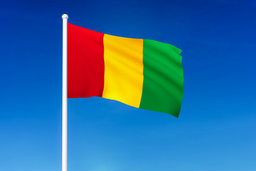 Waving flag of Guinea on the blue sky background