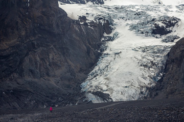 Lone figure of a tourist heading towards ice caves under the Gígjökull glacier near Þórsmörk with super jeeps coming her way