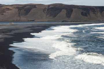 Reynisfjara black basalt sand beach in Vík í Mýrdal in Iceland on the west side of Mýrdalssandur glacial outwash plain as captured together with basalt columnar formations and cliffline