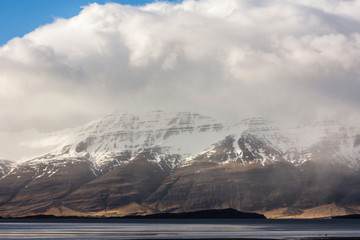 Icelandic fjords in Eastern part of island as pictured with snowstorm clouds and snow covered mountain ranges in the background