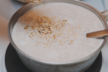 Falling oatmeal into hot milk. Steaming oatmeal.