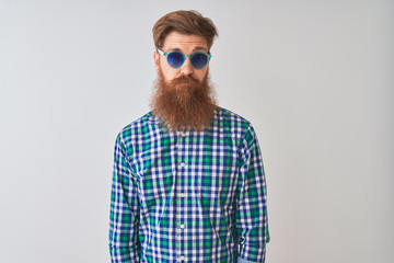 Young redhead irish man wearing casual shirt and sunglasses over isolated white background skeptic and nervous, frowning upset because of problem. Negative person.