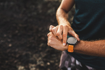 Young athletic man using fitness tracker or smart watch before run training outdoors. Close-up photo with dark background. - 297234938