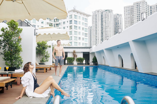 Young couple spending honeymoon at swimming pool of spa hotel