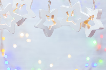 decorative white wooden stars garland lights. blurred background with winter holiday lights 
