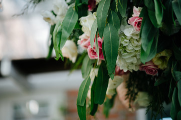 A bouquet of flowers decorated with pastel pink flowers and matching leaves hanging on the ceiling.