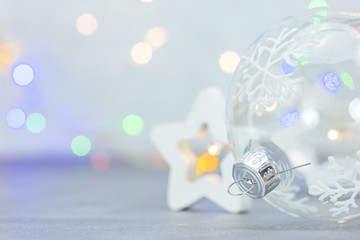 christmas glass ball with snowflakes and wooden star on defocused background with colorful lights