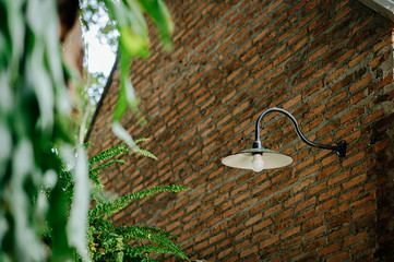 Lamp that is attached to a brick wall that has not been plastered.
