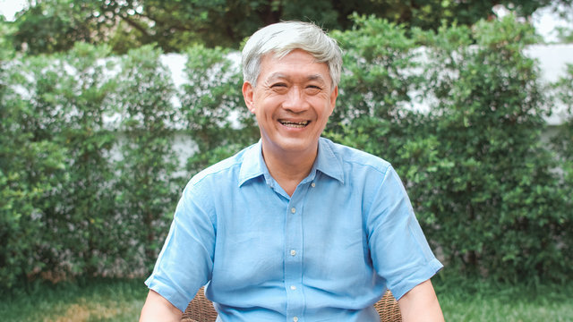 Portrait Asian Chinese senior man feeling happy smiling at home. Older male relax toothy smile looking to camera while lying in the garden at home in the morning concept.