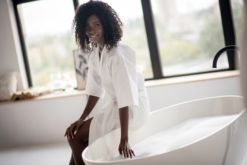 Dark-eyed woman trying water before having bath