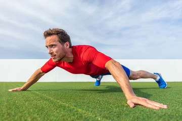 Wide grip pushup push-up variation advanced chest exercise demonstration by male trainer athlete man training at outdoor gym.