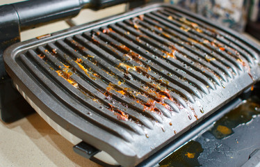 Dirty electric grill. Fat spots on a frying pan. Drops of fat.